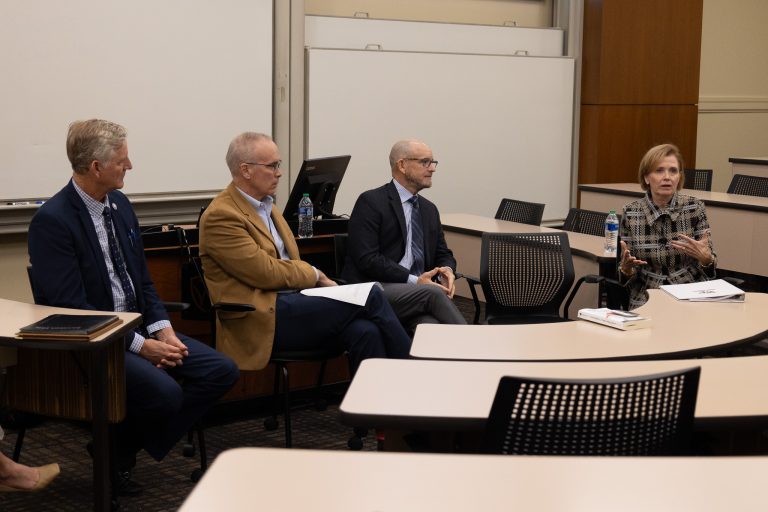 Four adults in professional wear having a conversation.