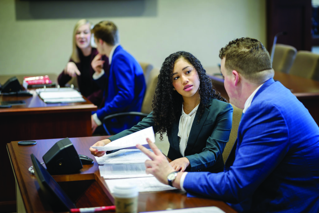 Four law school students performing a mock business trial/