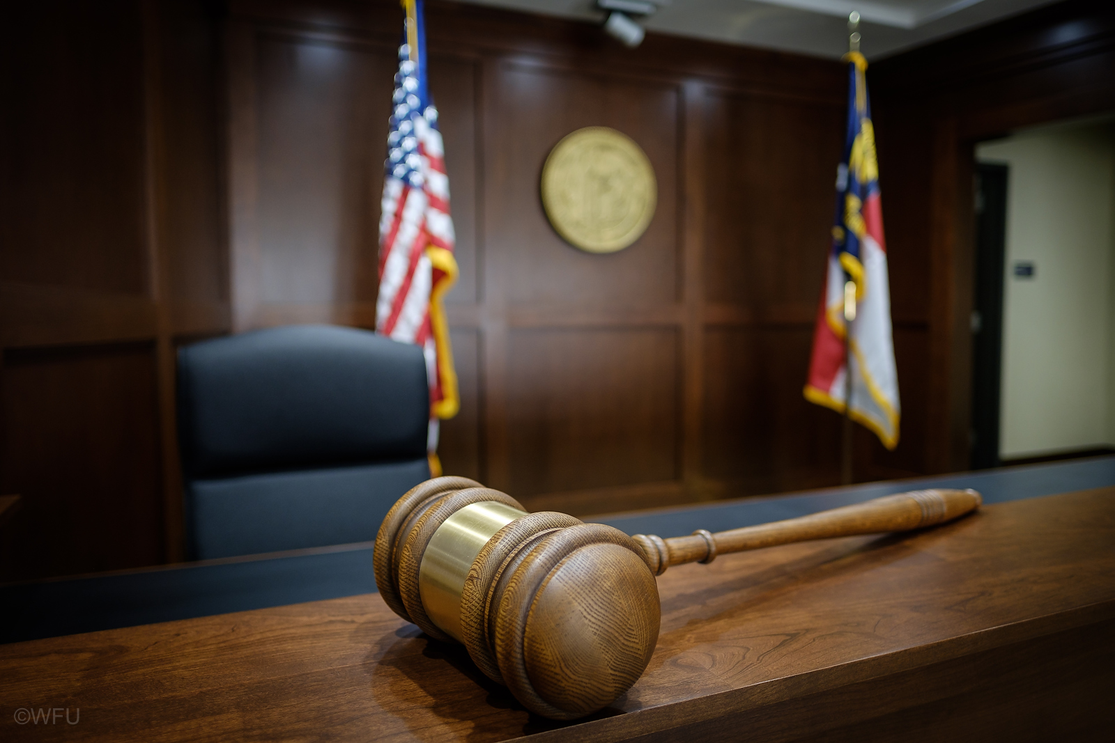 Gavel on table in front of American flag and North Carolina State flag in the North Carolina Business Court at the Wake Forest School of Law.