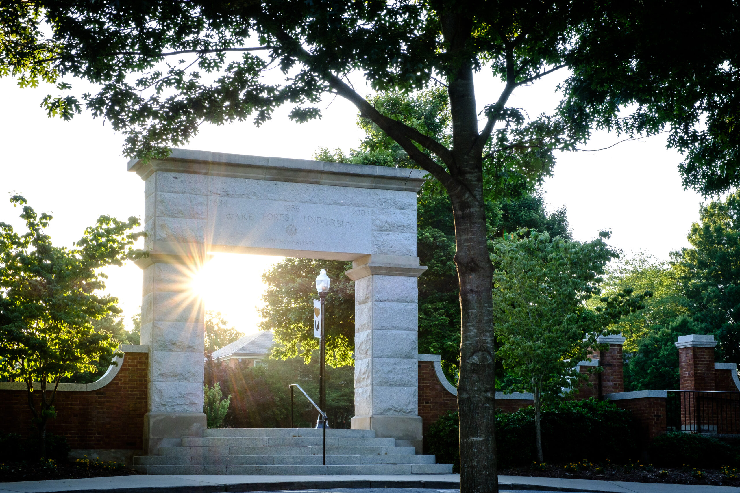 The sun shining through the stone arch to Hearn Plaza on the Wake Forest campus.