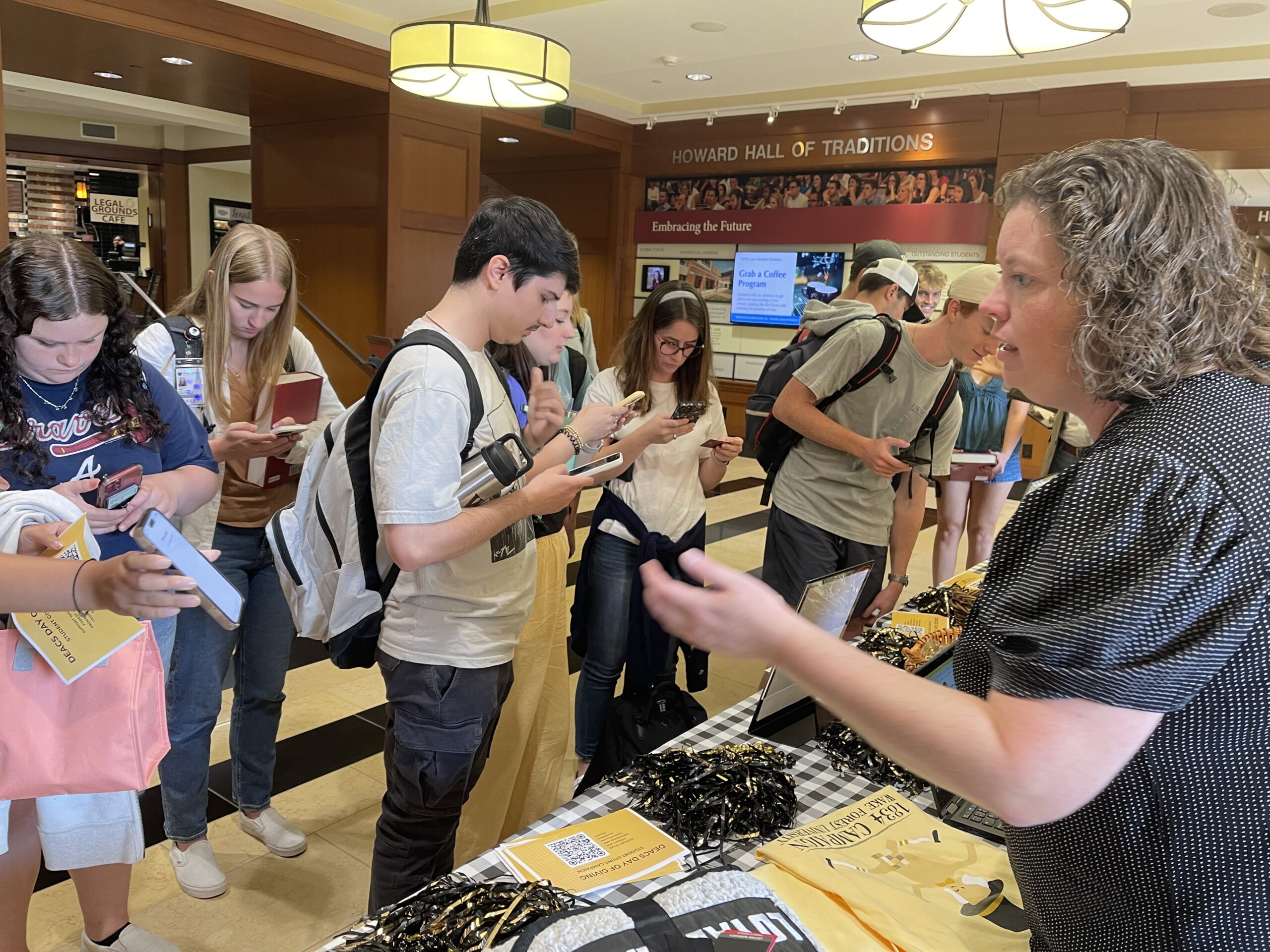 Students standing in front of table. Table is full with Wake Forest University souvenirs.