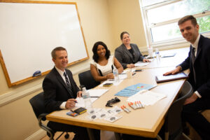 Four people in professional wear seated at a table posing for a picture.