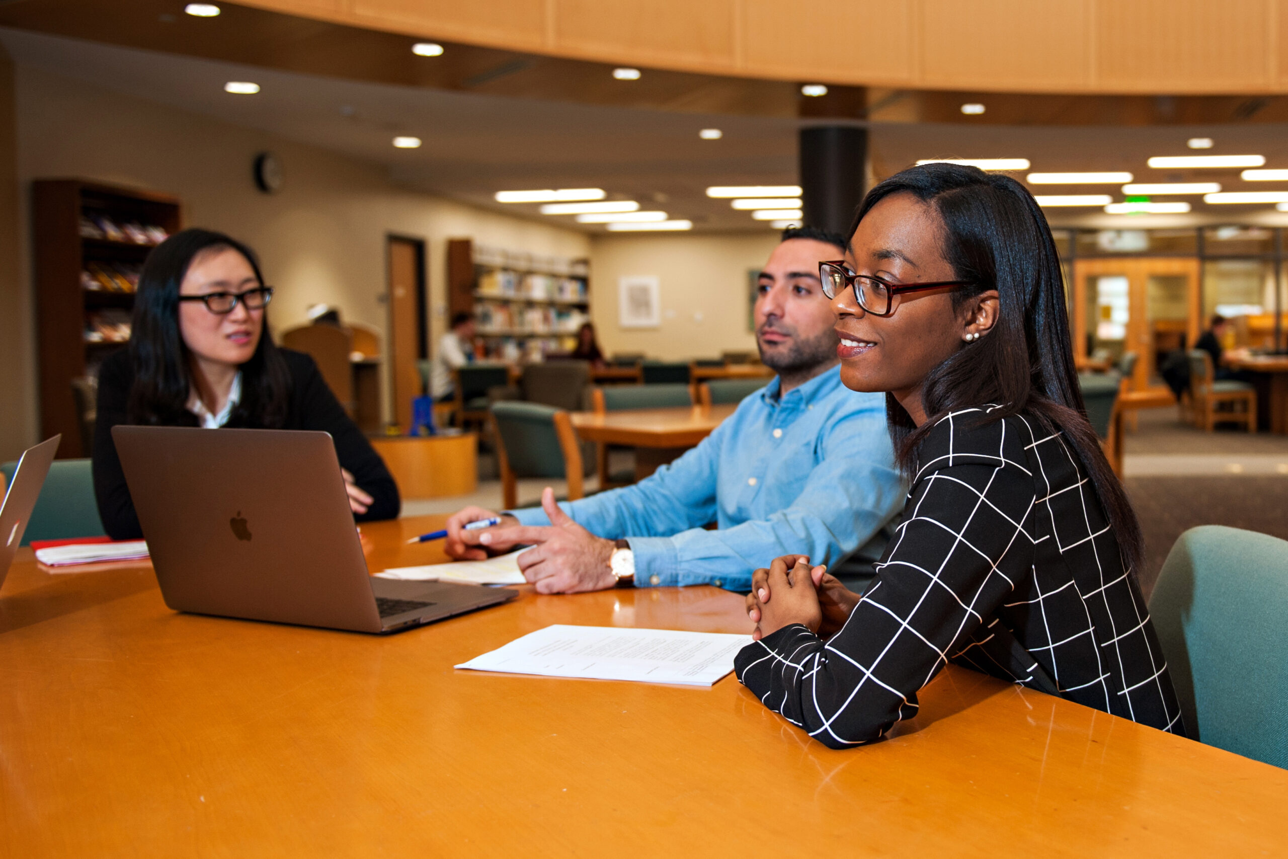 Three students engaging in a conversation at the Wake Forest library.