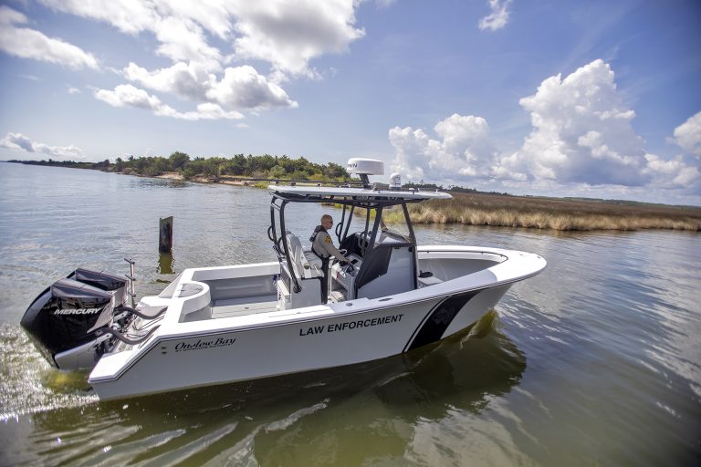 Man driving a motor boat on a river.