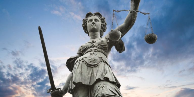 Sculpture of woman with sword in one hand and scale of justice in other hand.