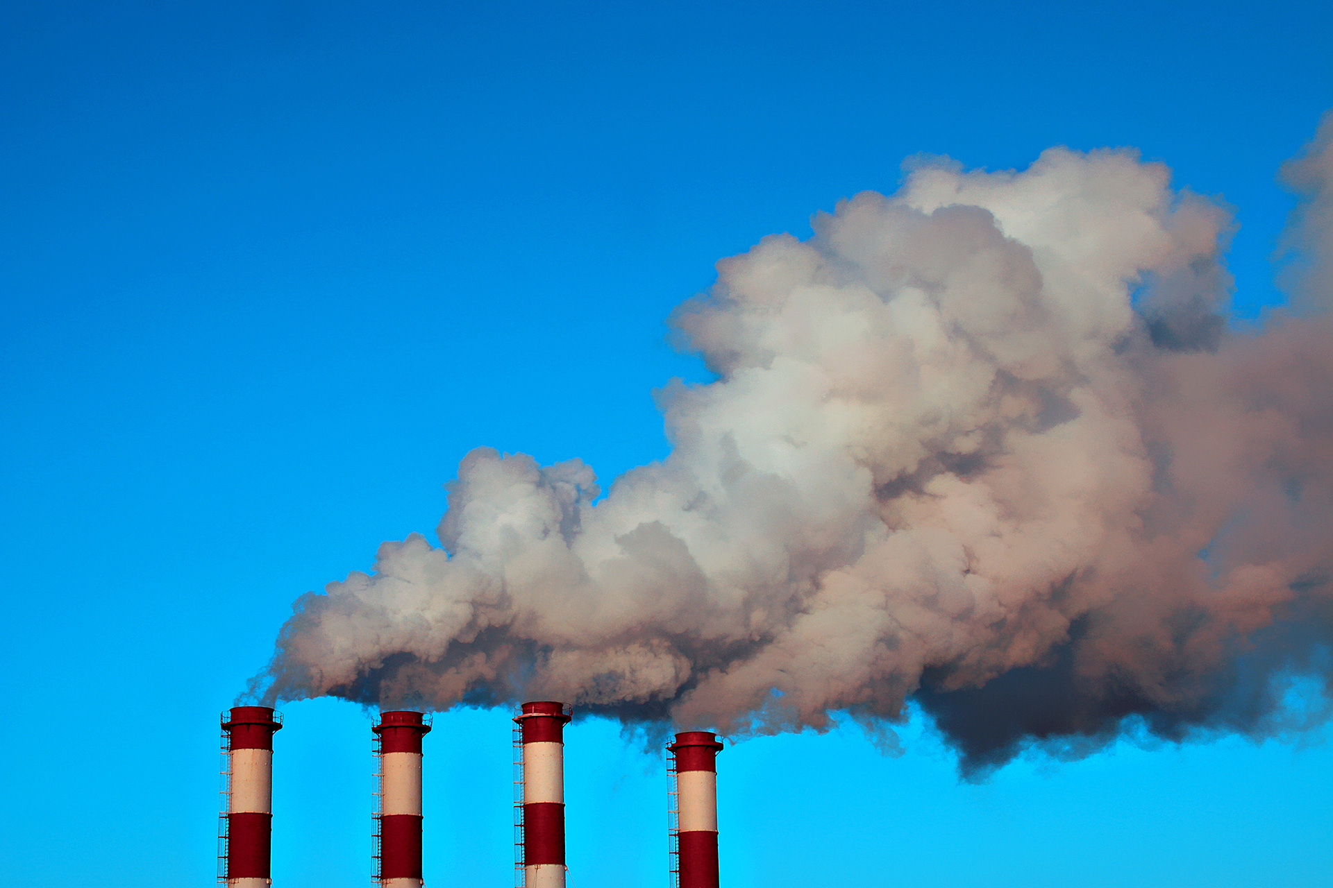 Four smokestacks with smoke coming out.