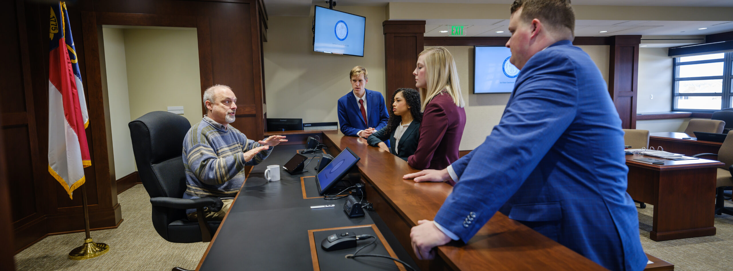 A professor talking with four Wake Forest Law students at Moot Court.