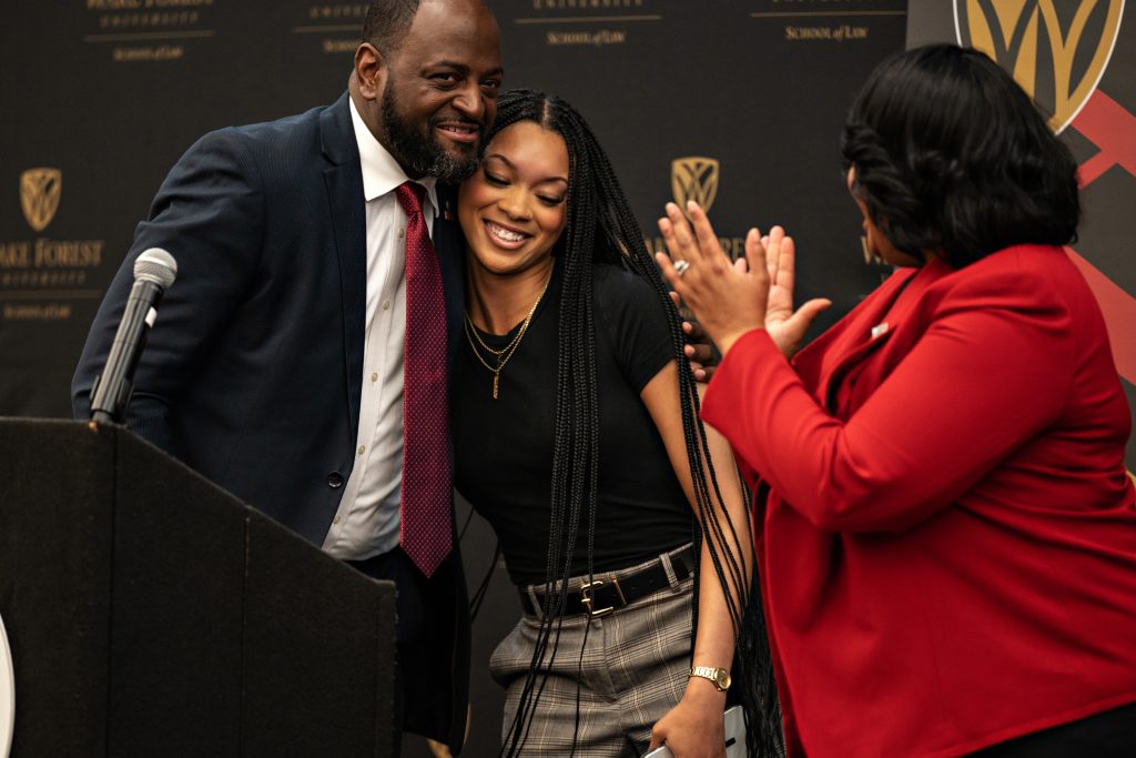 WSSU Provost Anthony Graham hugs WSSU student Kiara Lassiter as WSSU Chancellor Bonita Brown claps