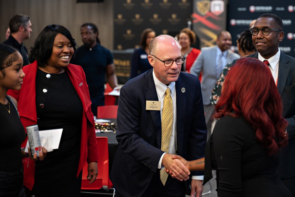 Wake Forest Law Dean Andy Klein shakes a woman's hand as WSSU Chancellor Bonita Brown smiles and looks on