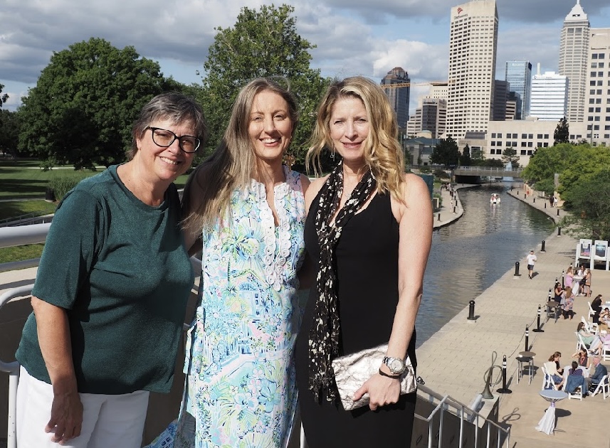 Professor Abby Perdue posing with two Legal Writing Institute members (women) in front of a cityscape and river