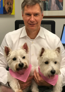 Gene Riddle holding two small white terrier dogs