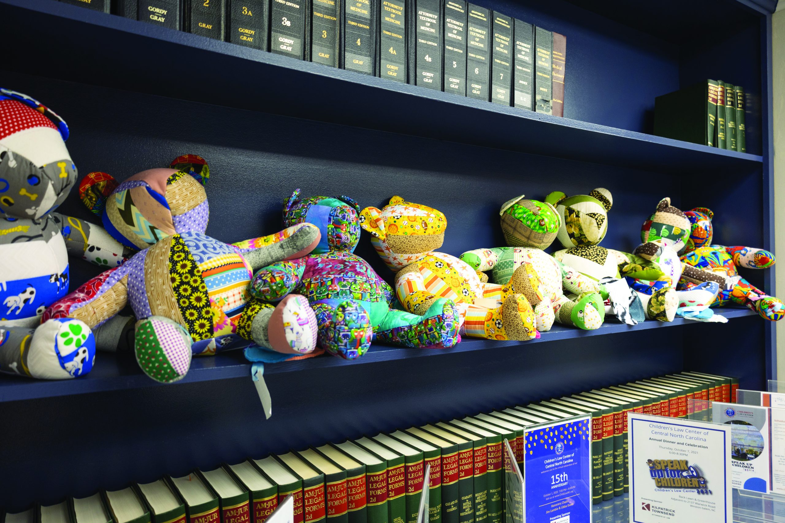 Photo of quilt-style teddy bears line the shelf alongside legal reporter volumes