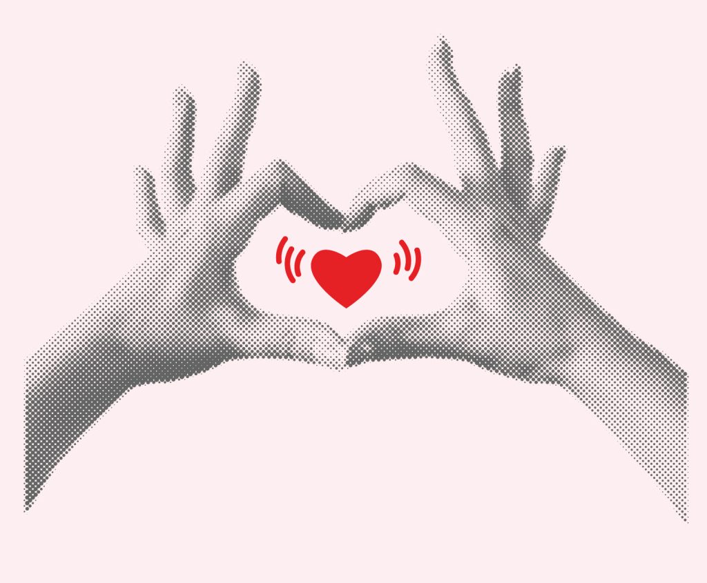 red heart framed by two hands mimicking a heart shape around it