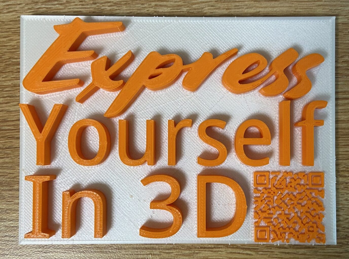 A 3D printed piece that says "Express yourself in 3D" and has a QR code 