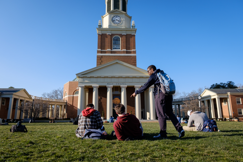 students sitting in the grass outside of campus