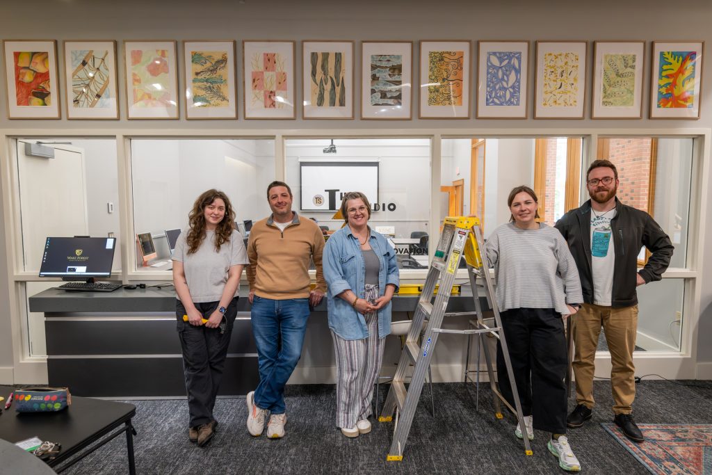 The team poses in front of hung artwork