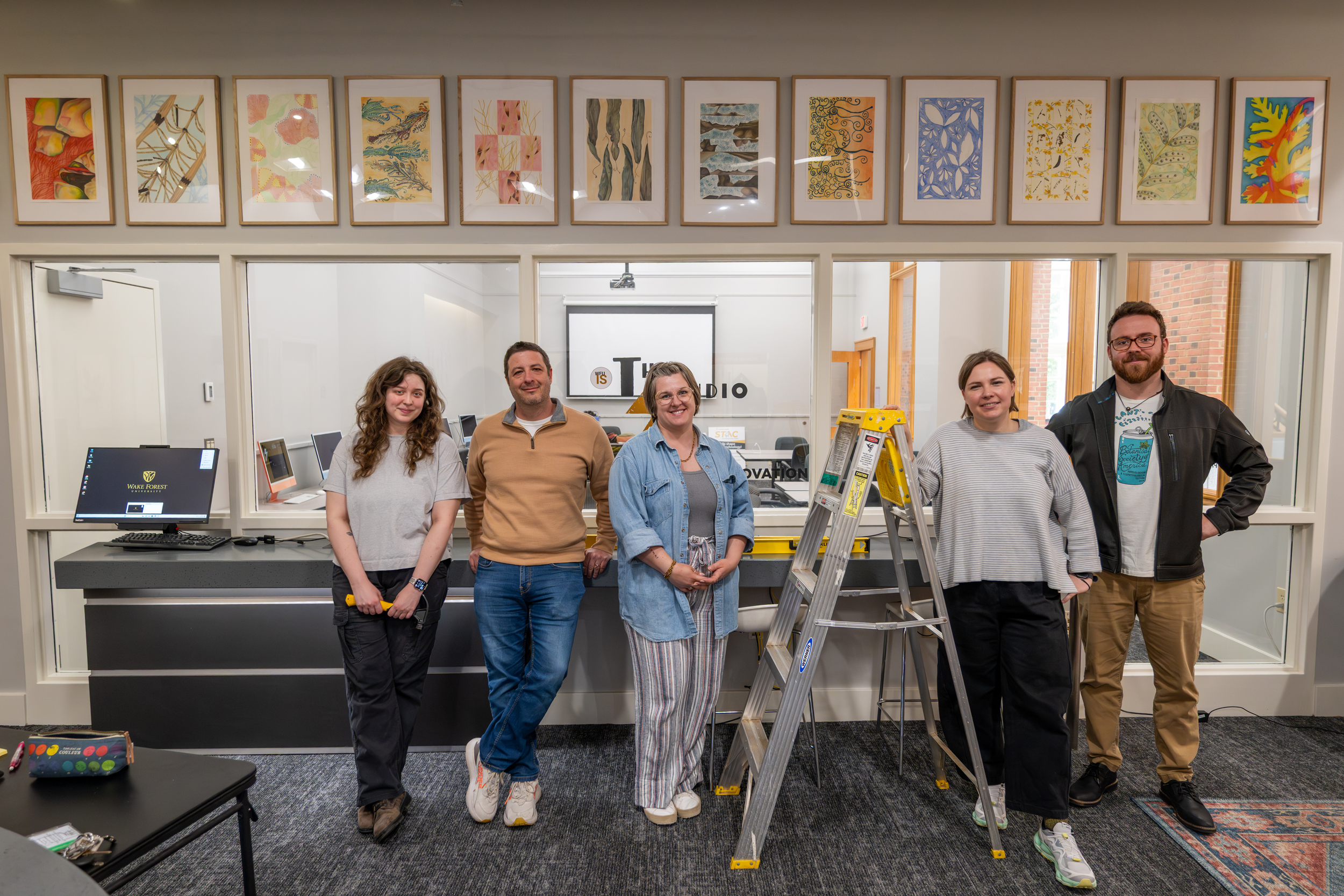 The team poses in front of hung artwork