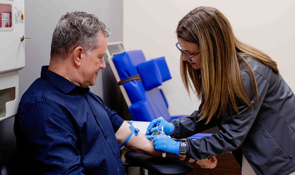 Lori Shores Cogdill drawing blood from particant HES Chair Peter Brubaker