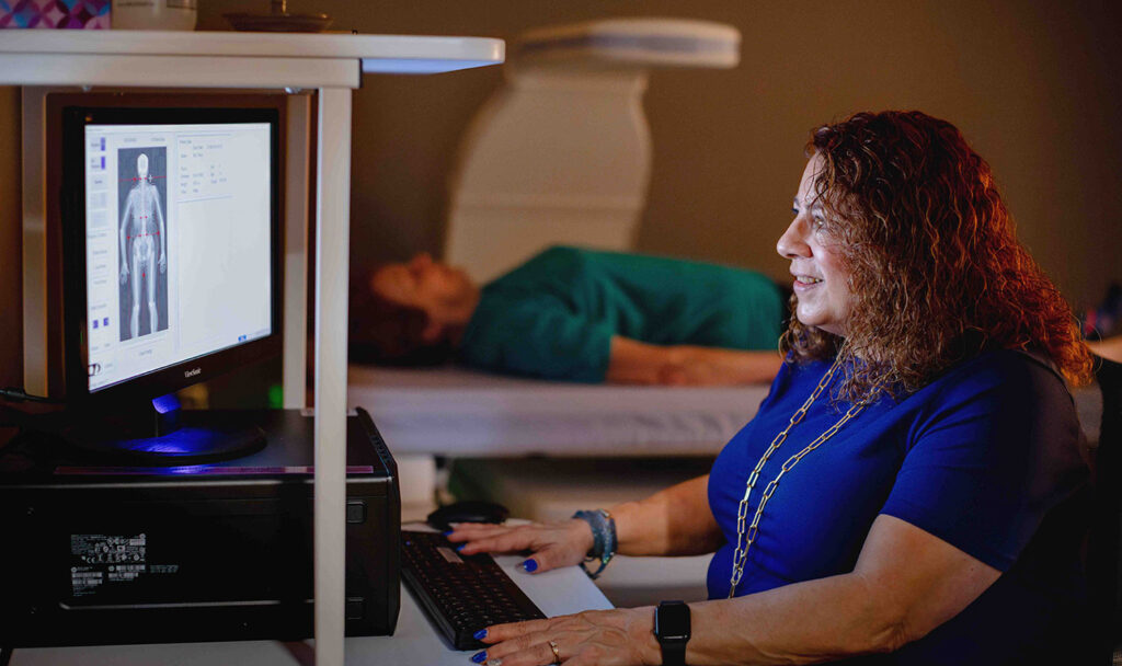 Sherri Ford reading a bone scan at the computer, participant in background