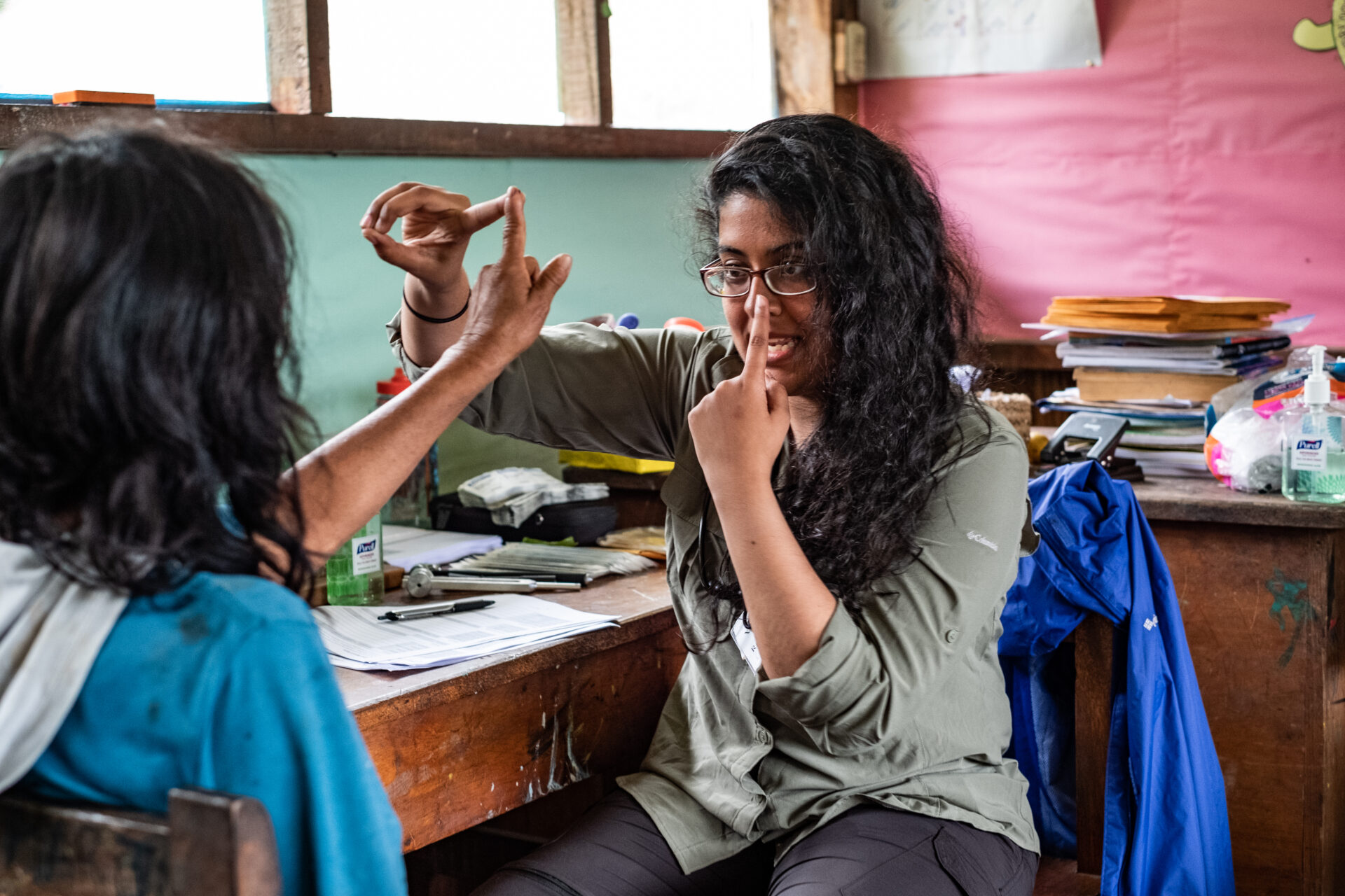 A researcher touchers her nose while touching the finger of a study participant