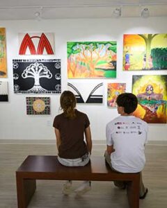 Photo of two people looking at paintings in the MINE exhibit