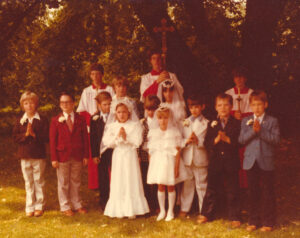 Figure 4: First Communion class photo featuring eleven communicants and three altar boys. They are standing together under a tree.