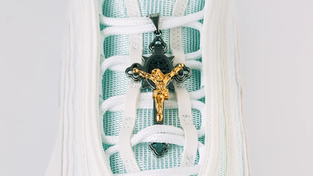 Figure 1: Close-up of gold and steel crucifix in the laces of MSCHF Jesus shoe.