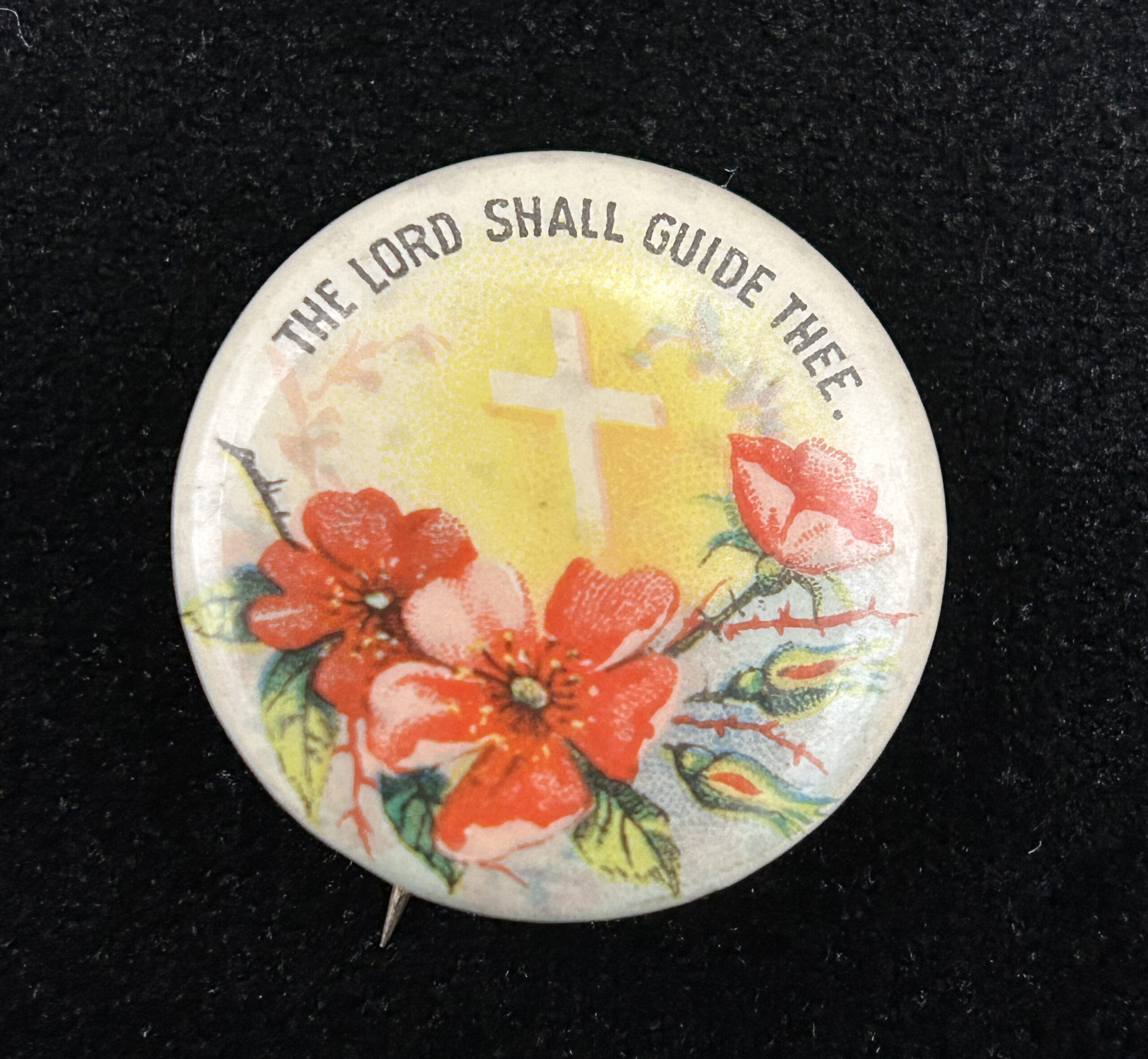 Figure 1: Pinback button by Whitehead & Hoag featuring a biblical passage, “The Lord Shall Guide Thee,” from Isaiah 58:11 with a floral motif and cross in the center. Photo by author.