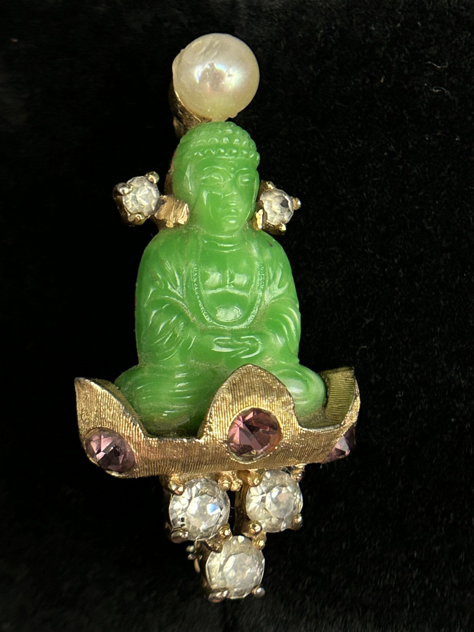 Figure 3: Close-up of J.J. Mazer brooch in which the meditating Buddha is surrounded by faux amethysts, rhinestones, and a “pearl.” Photo by author.