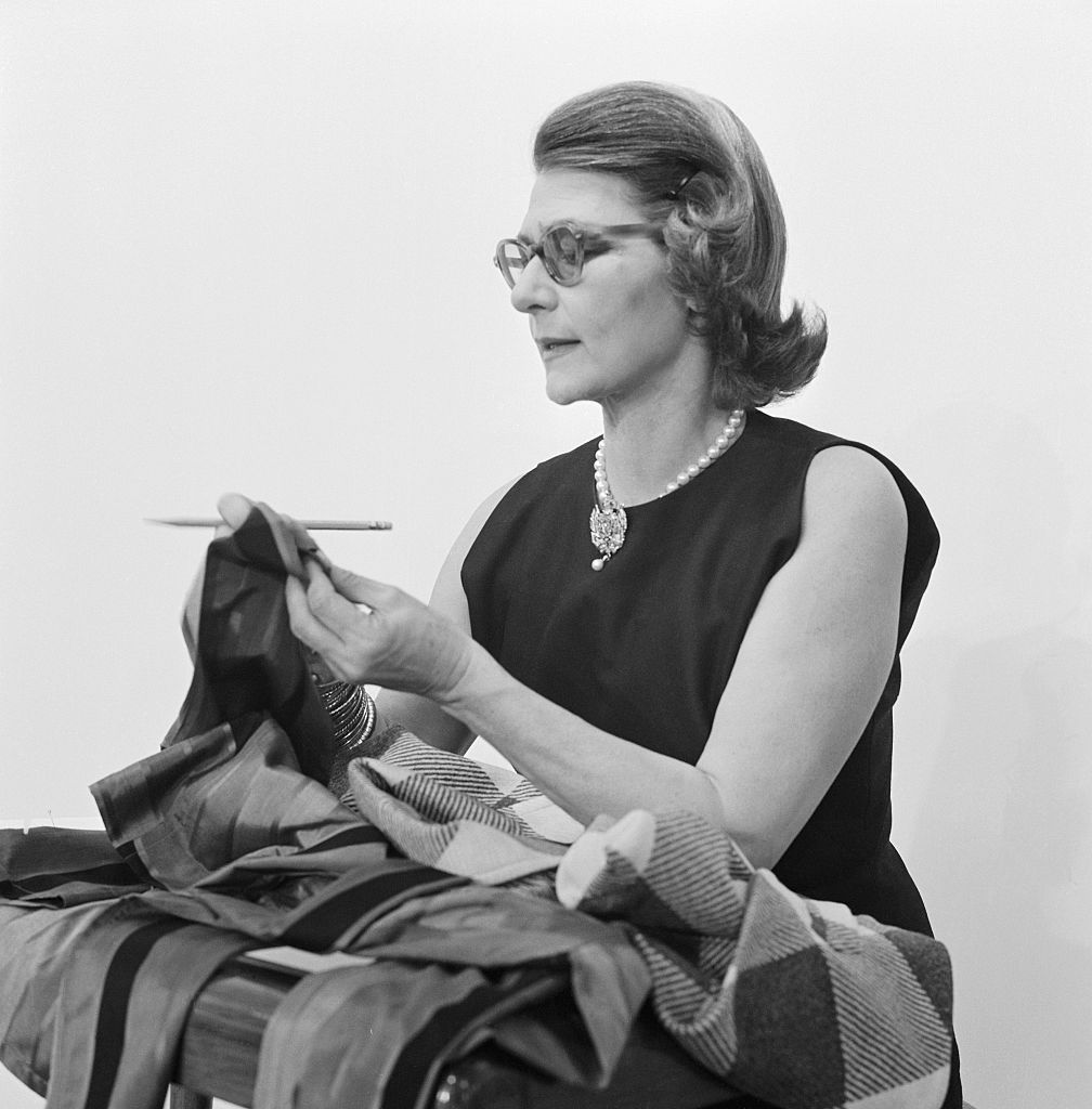 Portrait image of Pauline Trigère working with fabric.