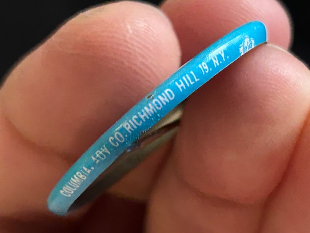 Blue side of button with the manufactured of the button labeled