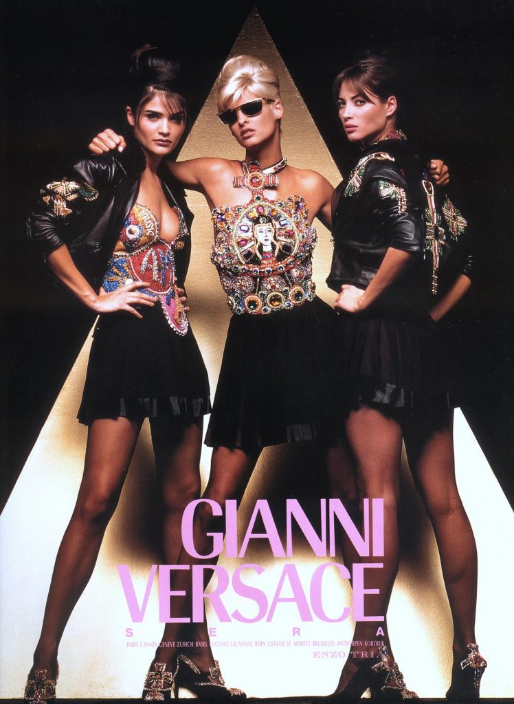 Figure 3: Advertisement for Versace’s Fall/Winter 1991Ready-to-Wear collection. In the center, supermodel Linda Evangelista wears the Mary-embellished halter, while the model to the right sports the cross-embellished biker jacket that was worn with it during the runway show. Note that all the models wear heels featuring cross embellishments. Fair use.