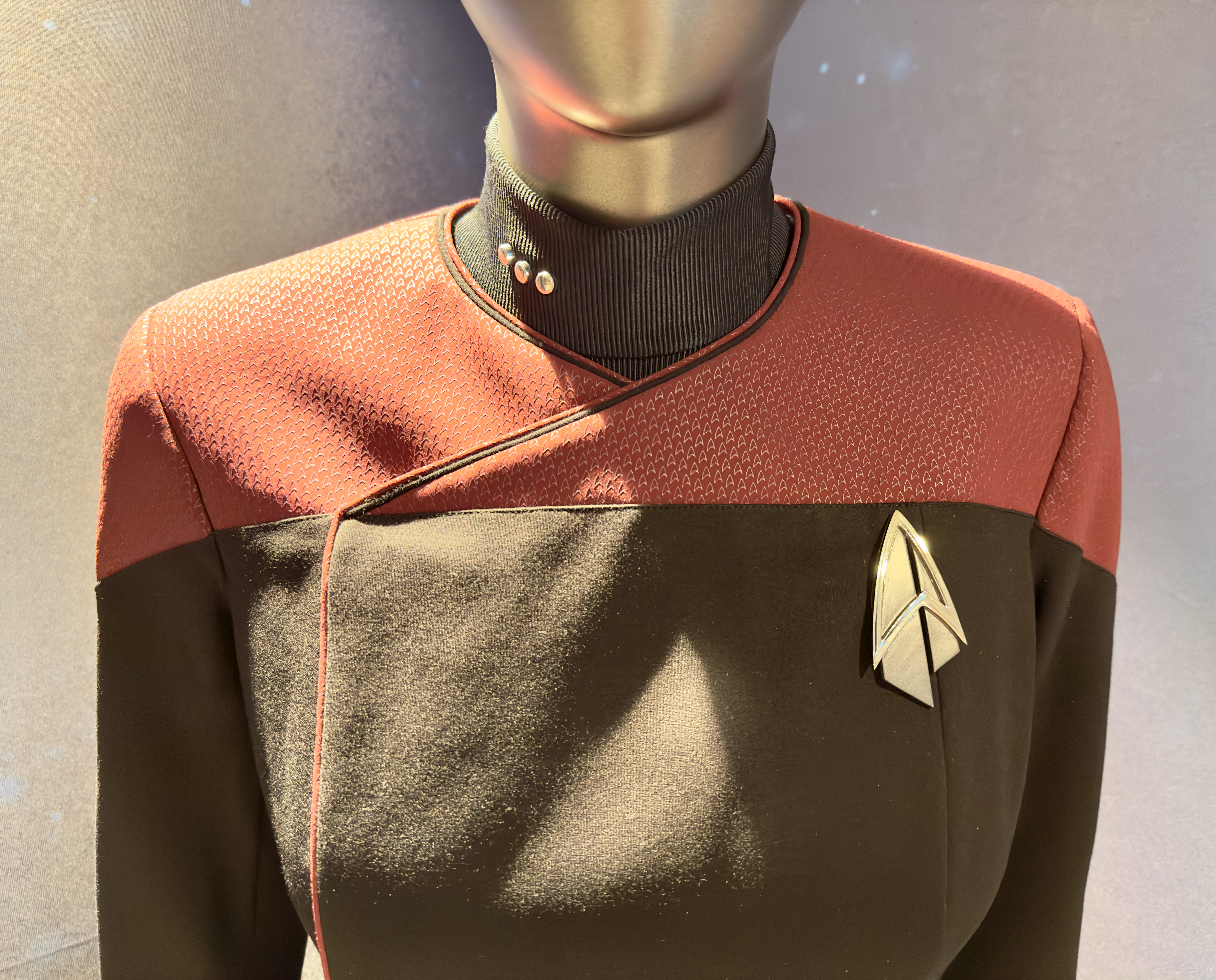 Figure 3: Close-up of a Star Trek uniform. Note simple lines, muted tones, and badge. Photograph by Fourthords. CC BY-SA 4.0.