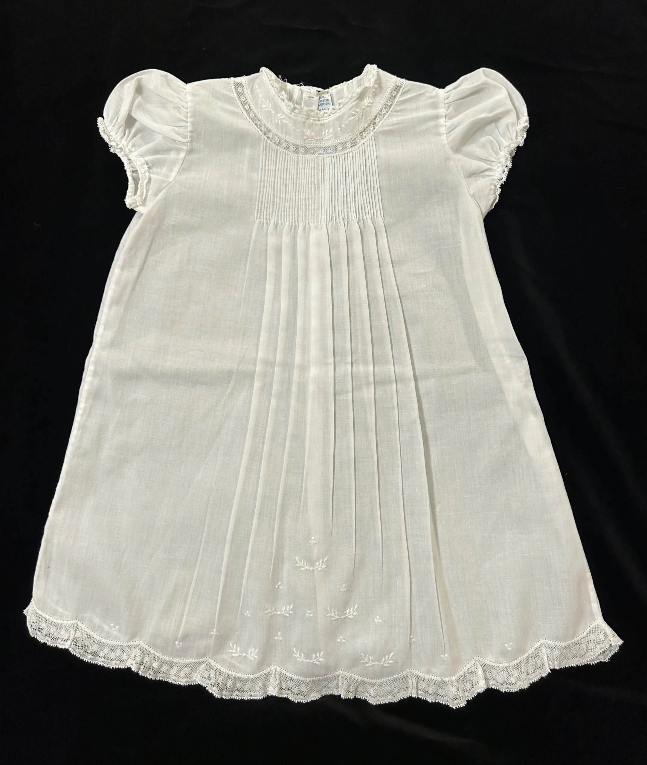 Figure 3: Another christening gown by Feltman Brothers c. 1970s or 1980s. This one features delicate pintucks, lace trim, and a hand-embroidered laurel design. Photograph by author ©. 