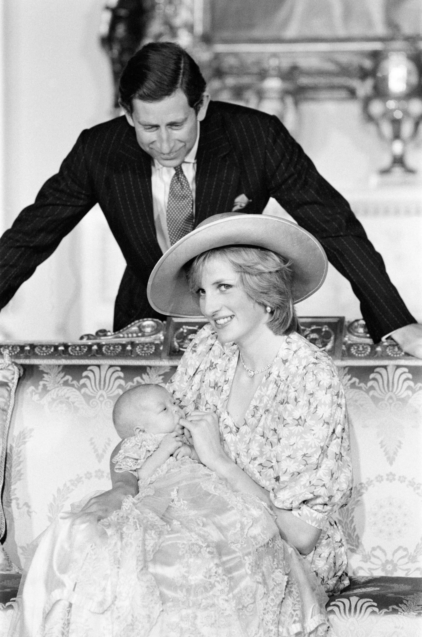 Figure 5: Photograph of Princess Diana holding Prince William with Prince Charles looking on. Prince William wears the heirloom gown created in 1841 for King Edward VII. Photograph © Mirrorpix/Alamy.