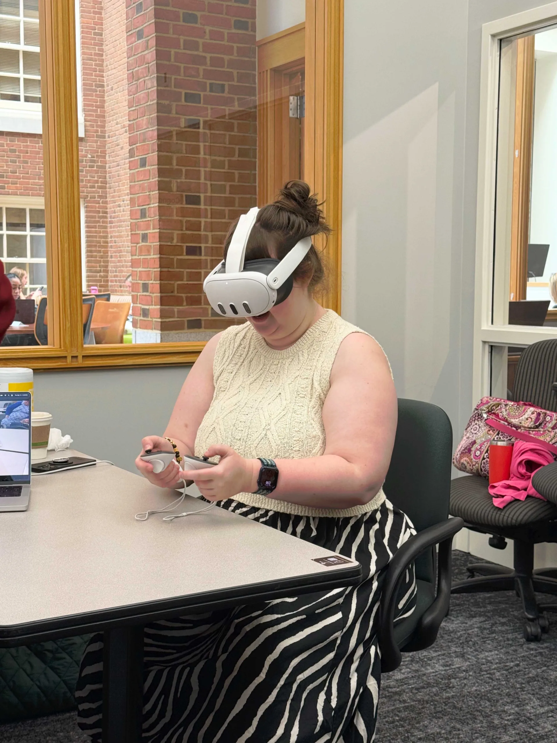 Sidney Beeman wears a white VR headset and holds a controller in each hand.
