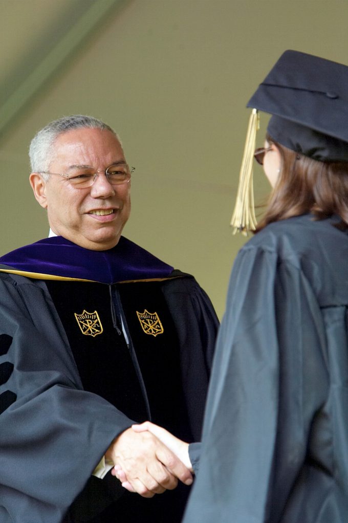 U.S. Secretary of State Colin Powell shakes hands with new graduates.