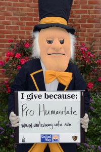 The Demon Deacon holds a sign that says Pro Humanitate