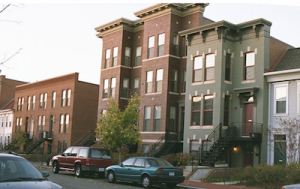 Several apartment buildings with cars parked on the street outside