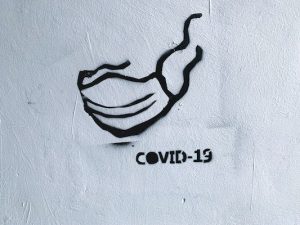 Graffiti stencil that says "COVID-19" beneath a face mask
