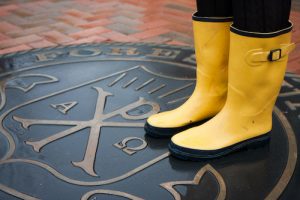 Student with yellow rain boots standing on Wake Forest seal