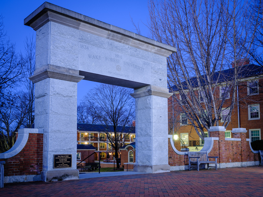 Photo at dusk of the stone arch that marks the entrance to Hearn Plaza. "Wake Forest University" and the years 1834, 1956 and 2006 are carved in stone.