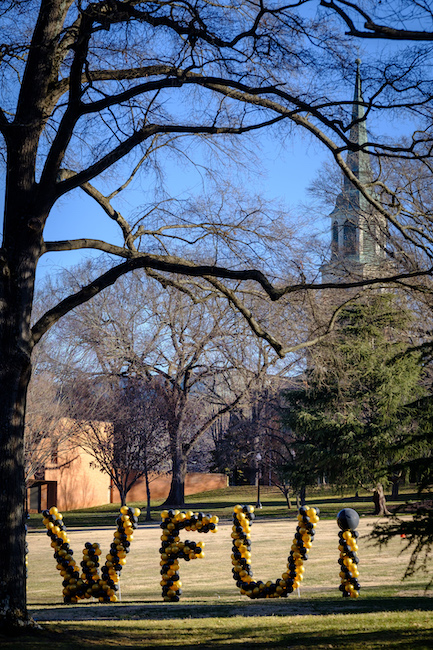 Photo of black and gold balloons forming large "W-F-U" letters on Davis Field with Wait Chapel in the background