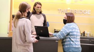 Photo of two students and a staff member wearing masks at the IS Service Desk