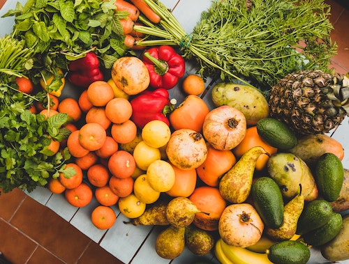 Photo of a pile of fruits, vegetables, and herbs (oranges, cucumbers, carrots, peppers, mint)