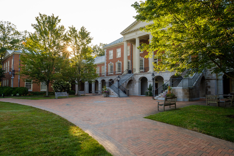 Photo of Reynolda Hall as seen from Hearn Plaza with the sun peeking through the trees