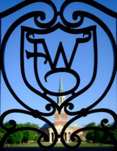 Wait Chapel is visible through an ironwork WF logo, on the campus of Wake Forest University