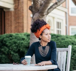 Photo of Wake Forest faculty member Rowena "Rowie" Kirby-Straker sitting at an outdoor table with a cup of coffee