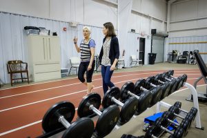Wake Forest Health and Exercise Science professor Kristen Beavers talking and walking with an older adult female around an indoor track at the Clinical Research Center