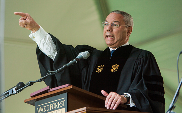 Photo of General Colin L. Powell wearing Wake Forest University regalia standing behind a podium that says "Wake Forest University." He is speaking into a microphone and pointing toward a crowd gathered for the 2004 WFU Commencement Ceremony, where Powell was the keynote speaker.